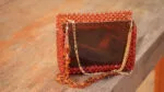 Gros plan sur la façade en acrylique ambre brillant et la double chaîne du sac à main