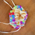 Vue de dessus du mini sac seau perlé multicolore et de sa doublure satin crème