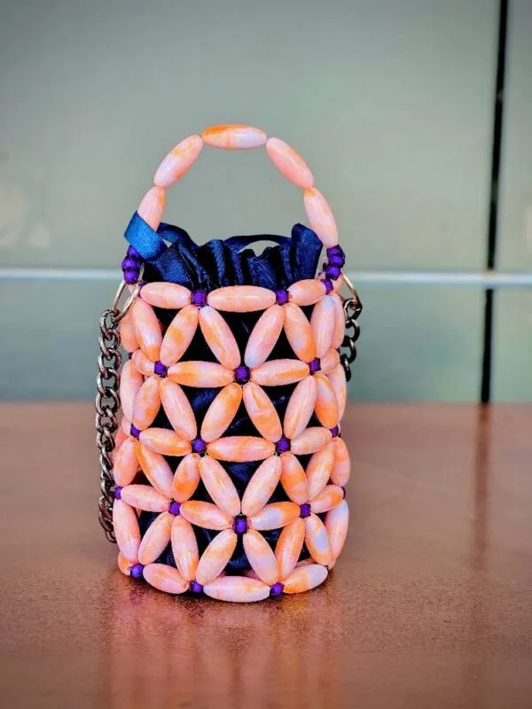 Vue de face du mini sac perlé rose pêche et violet à motif floral, doublure satin bleu marine