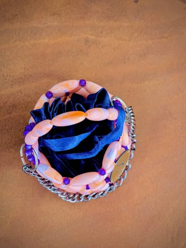 Vue de dessus du mini sac perlé rose pêche et violet laissant voir la doublure satin bleu marine