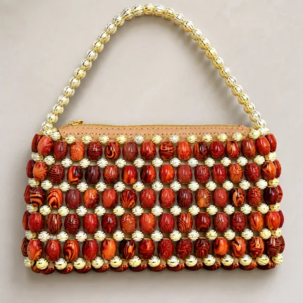 Vue de face du sac Malika Kongo sur fond beige, perles marron et dorées en quadrillage, fermeture zippée