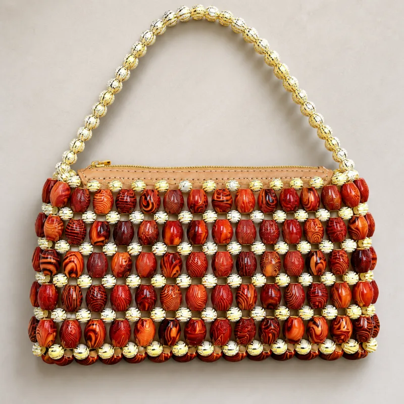 Vue de face du sac Malika Kongo sur fond beige, perles marron et dorées en quadrillage, fermeture zippée