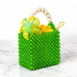 Sac Zawadi vu de face sur marbre blanc, perles vert émeraude, poignée en perles nacrées et fleur jaune décorative
