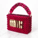 Sac Zola Nyota vu de profil sur marbre blanc, perles rouges facettées et insert en tissu wax africain