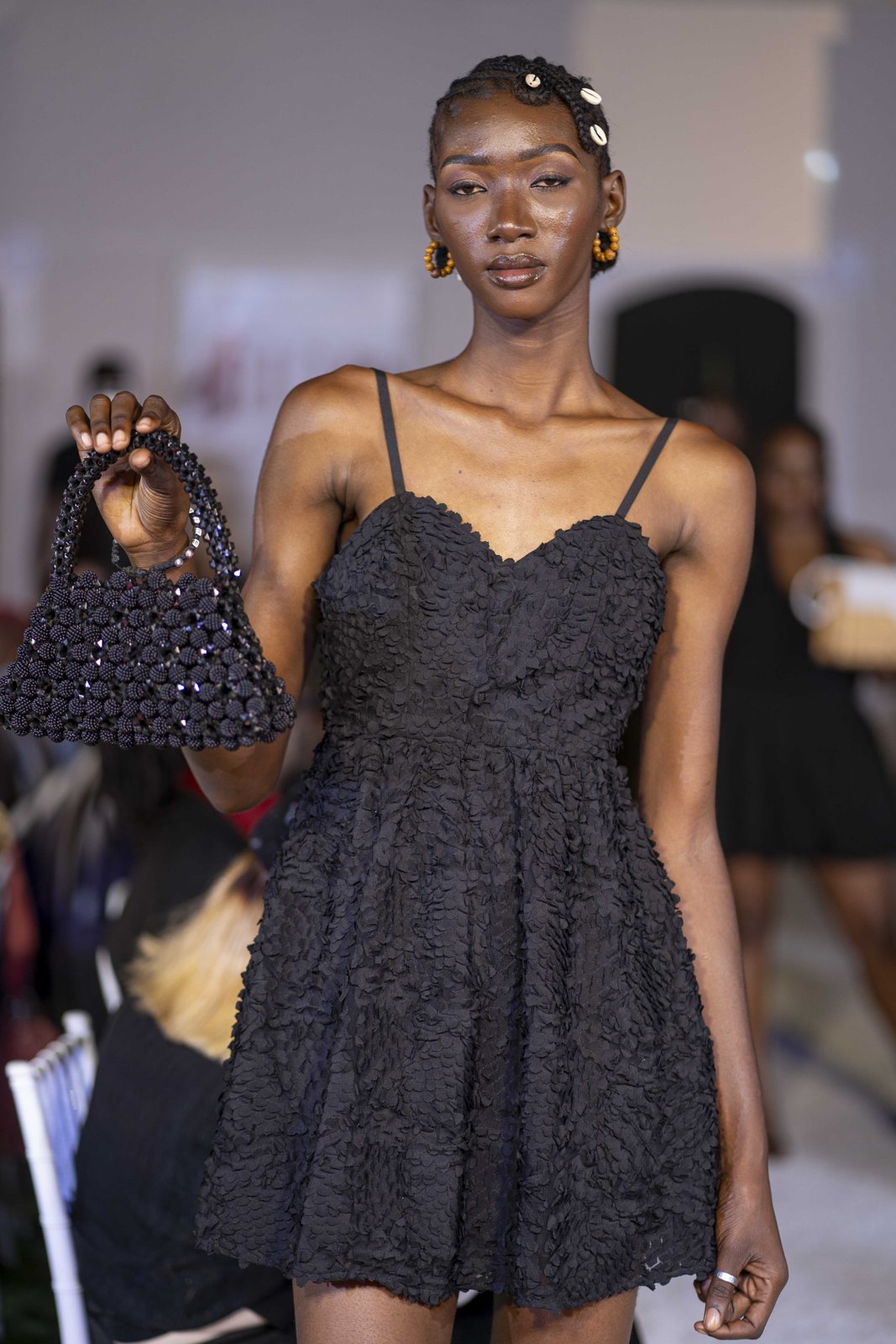 Mannequin en robe noire présentant un sac à main noir en perles.