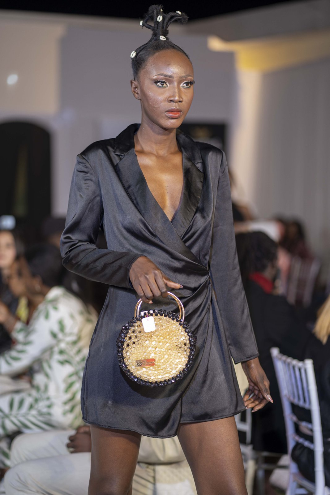 Mannequin en tenue noire portant un sac rond en perles claires et dorées.